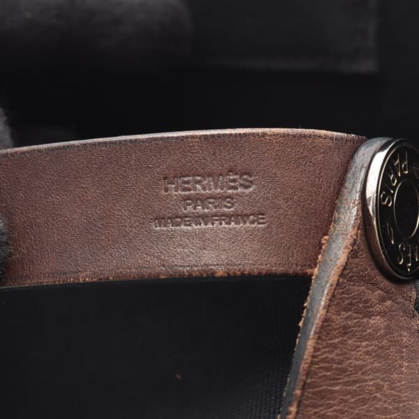 Black canvas tote bag with leather-trimmed handles and a detachable strap.