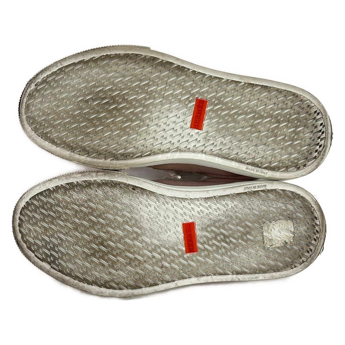 White leather low-top sneakers with red trim detailing.