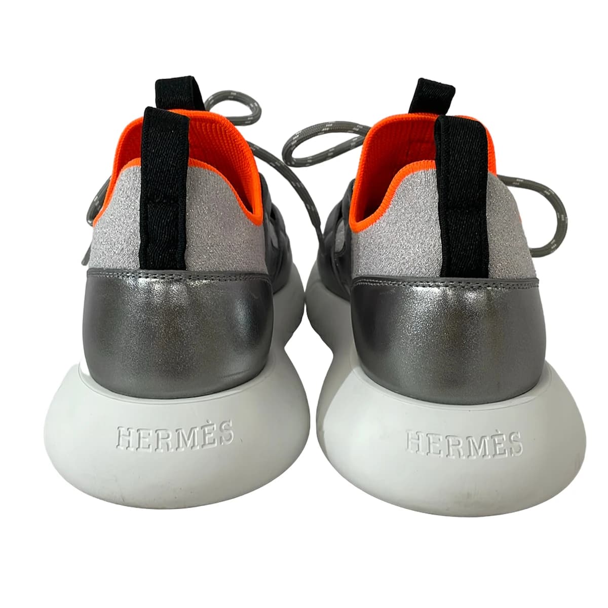 Grey low-top trainers with silver side panelling and white soles.