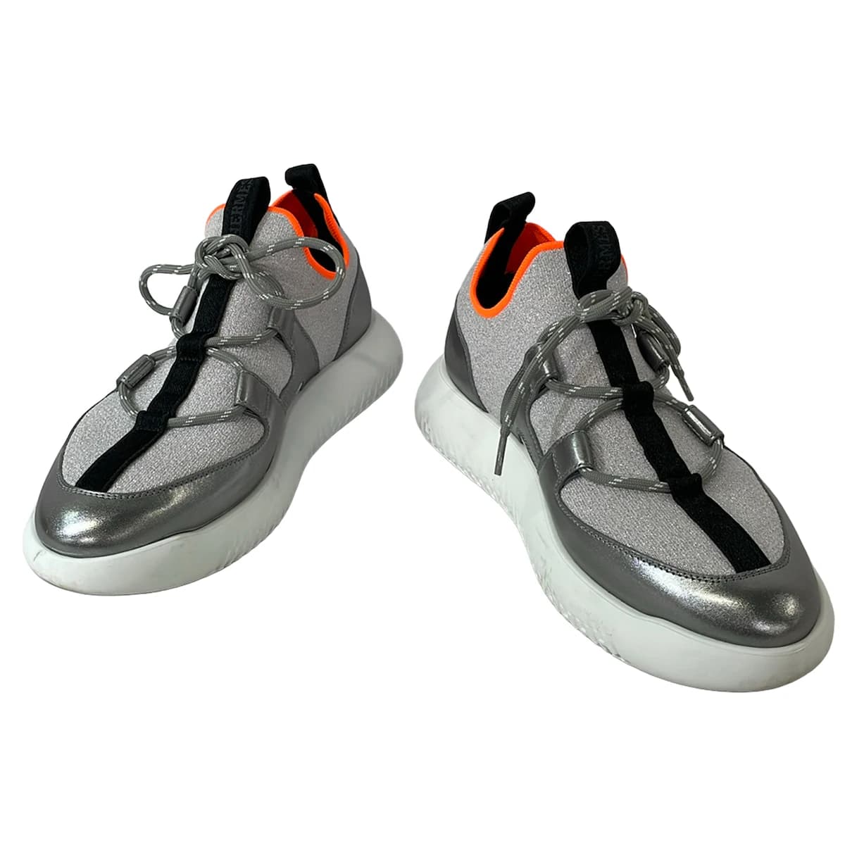 Grey low-top trainers with silver side panelling and white soles.