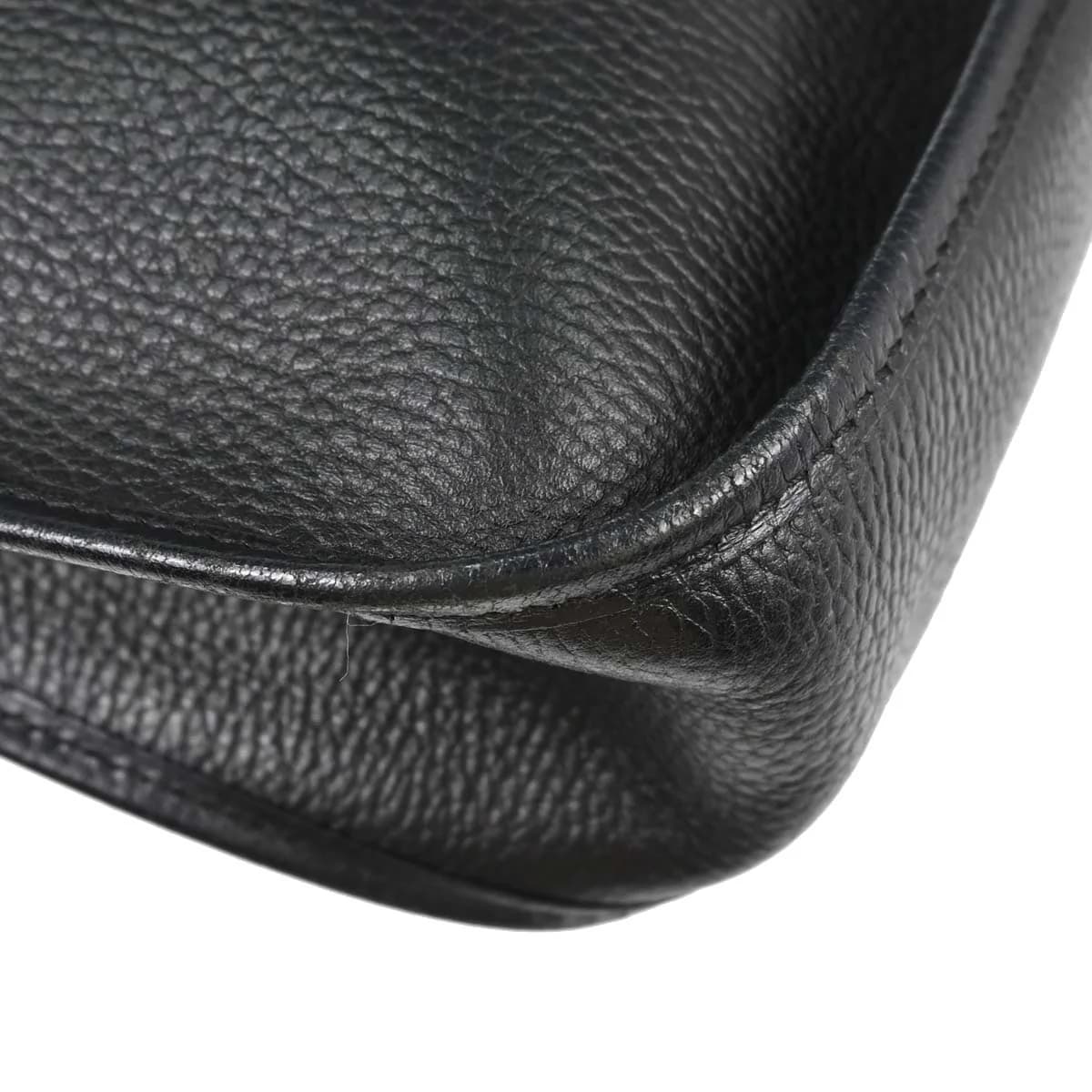 Black grained leather shoulder bag with a perforated H on the front and a long strap.
