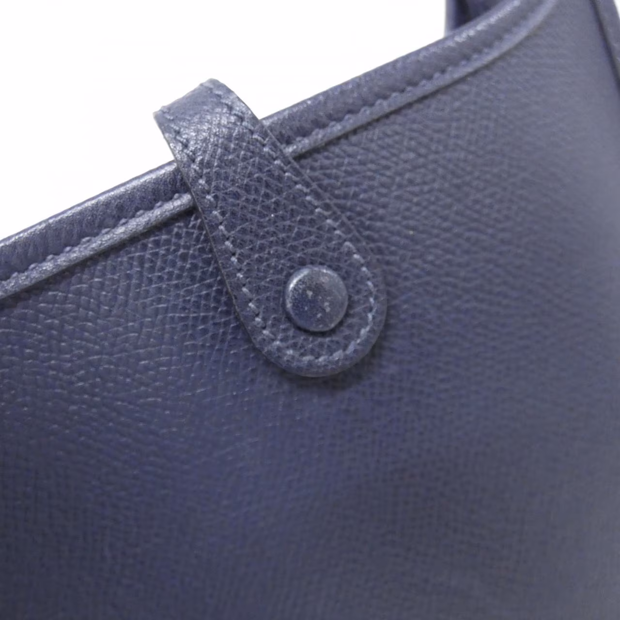 Small leather shoulder bag with perforated H cut-out on the front panel and a long flat strap