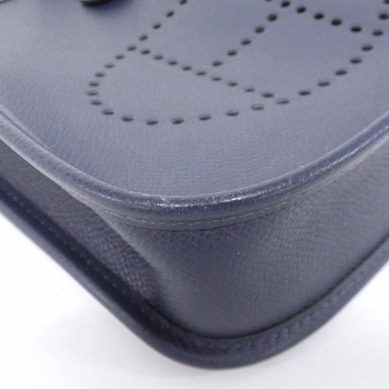Small leather shoulder bag with perforated H cut-out on the front panel and a long flat strap