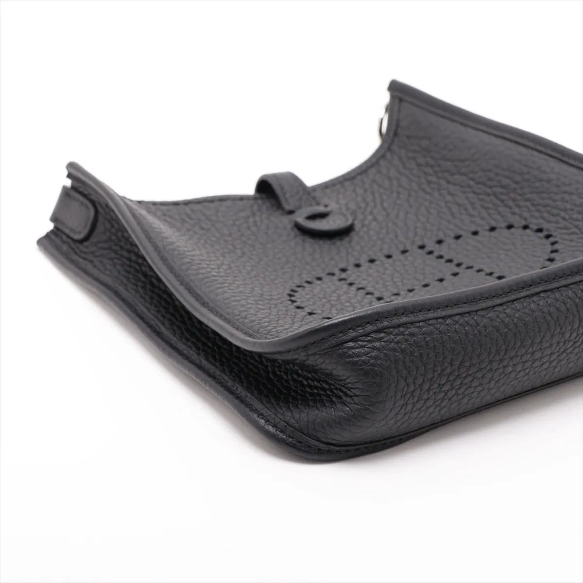 Small pouch-style leather bag in black with perforated logo on the front panel and a flat adjustable strap.