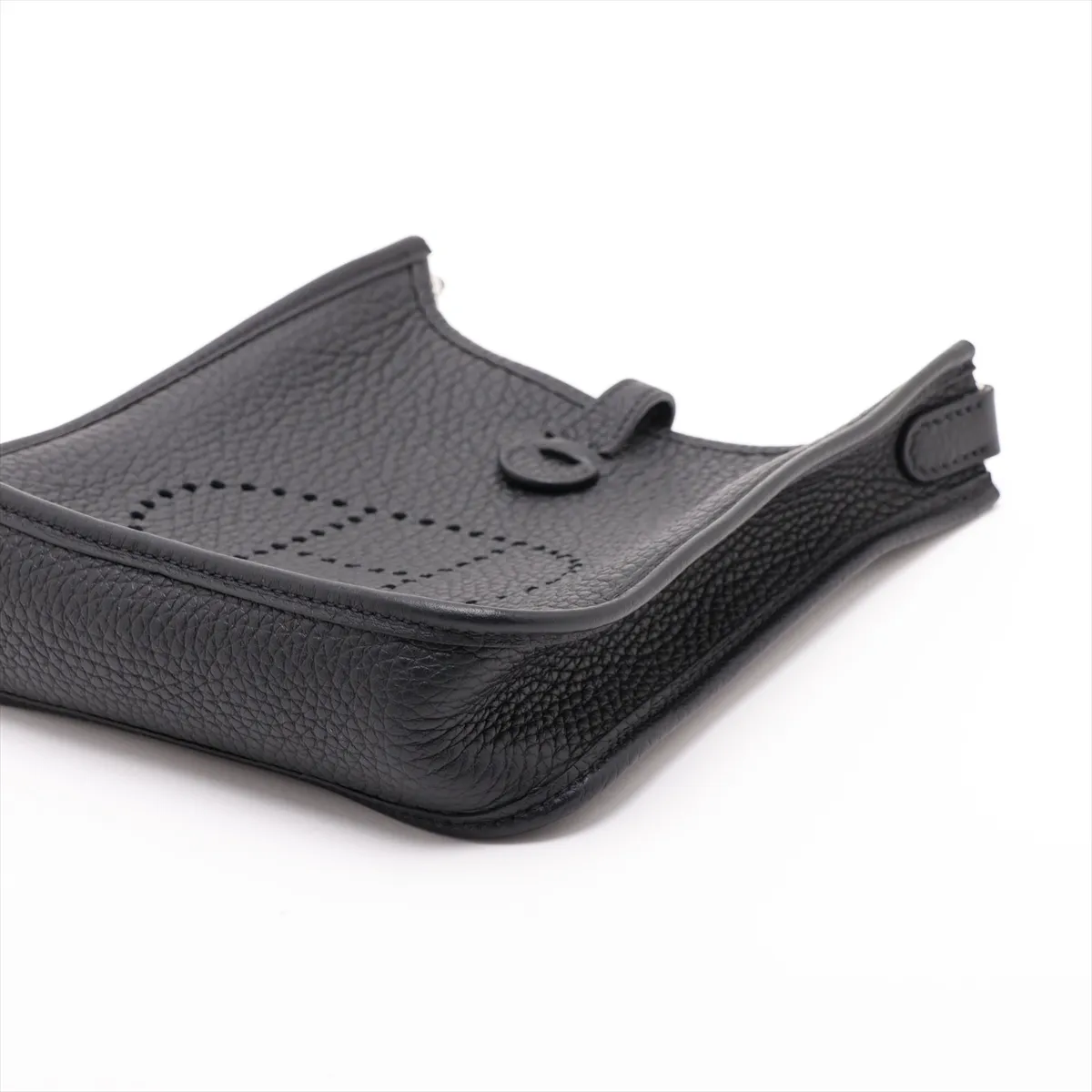 Small pouch-style leather bag in black with perforated logo on the front panel and a flat adjustable strap.