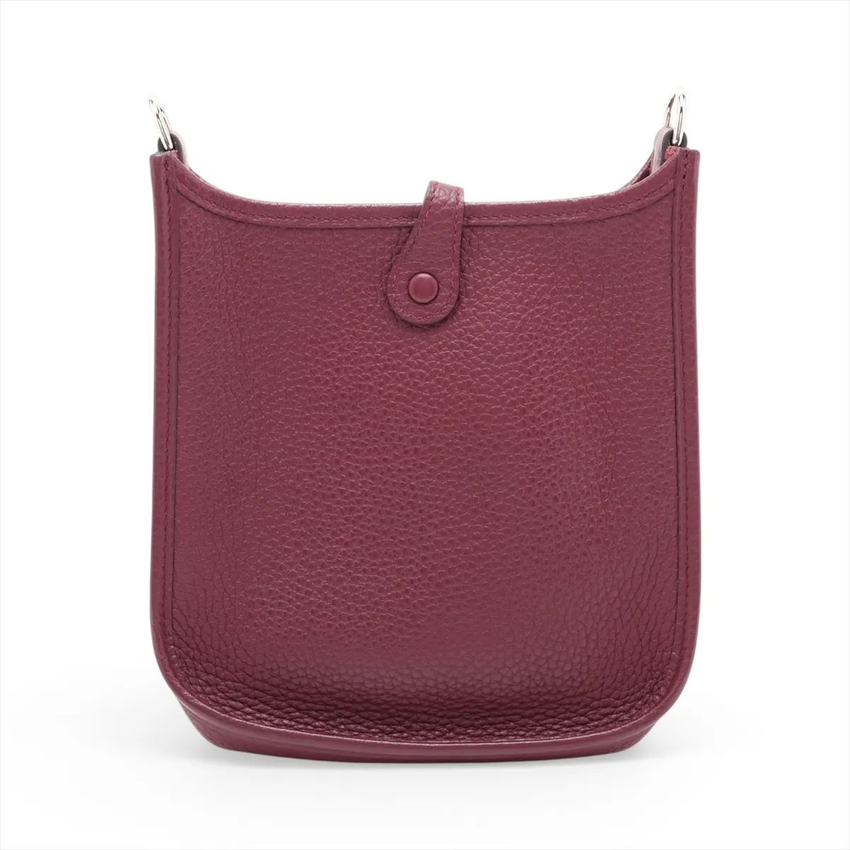 Small deep red leather shoulder bag with perforated H on the front and a long woven strap.