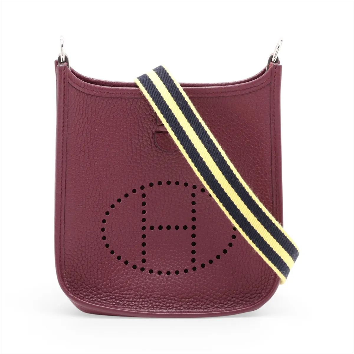 Small deep red leather shoulder bag with perforated H on the front and a long woven strap.
