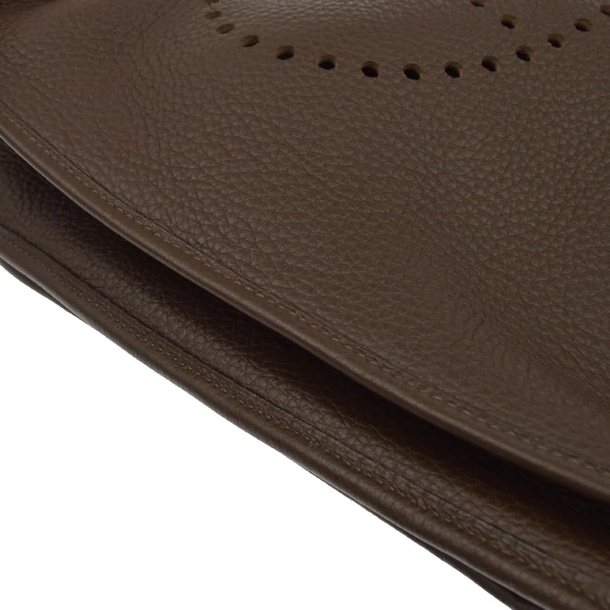 Brown grained leather shoulder bag with perforated design on the front and a wide strap