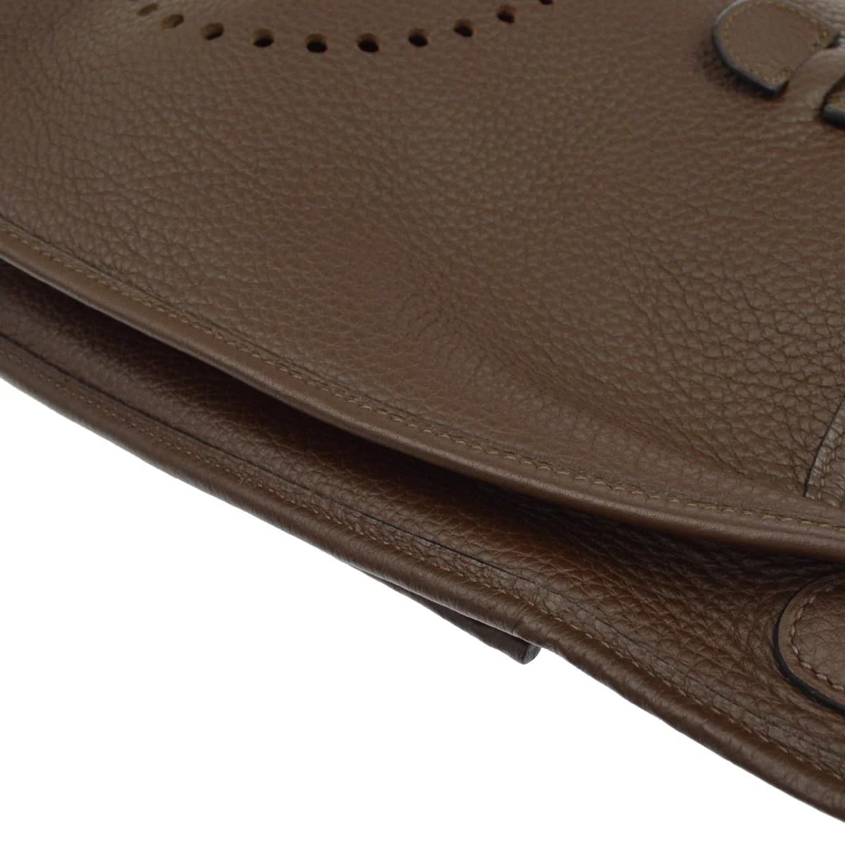 Brown grained leather shoulder bag with perforated design on the front and a wide strap