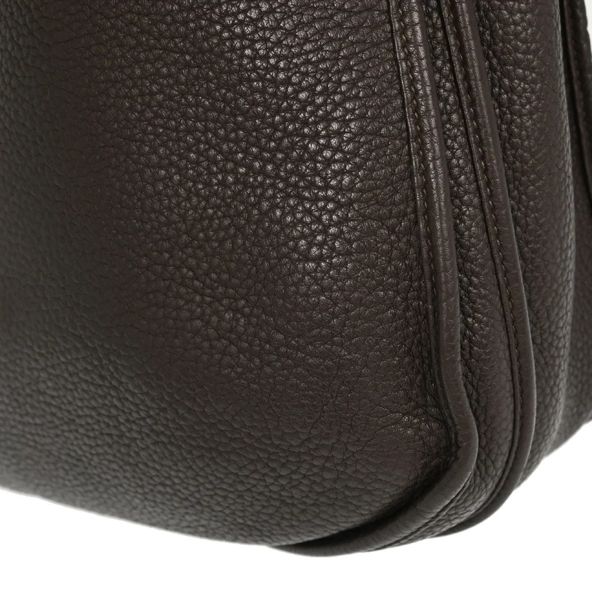 Brown leather shoulder bag with perforated logo front panel and long flat strap.