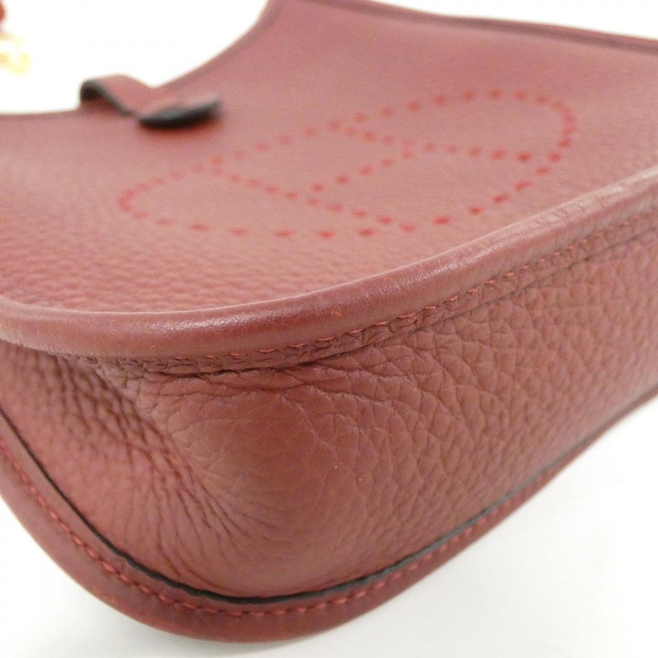 Small leather shoulder bag with perforated H on the front and woven strap.