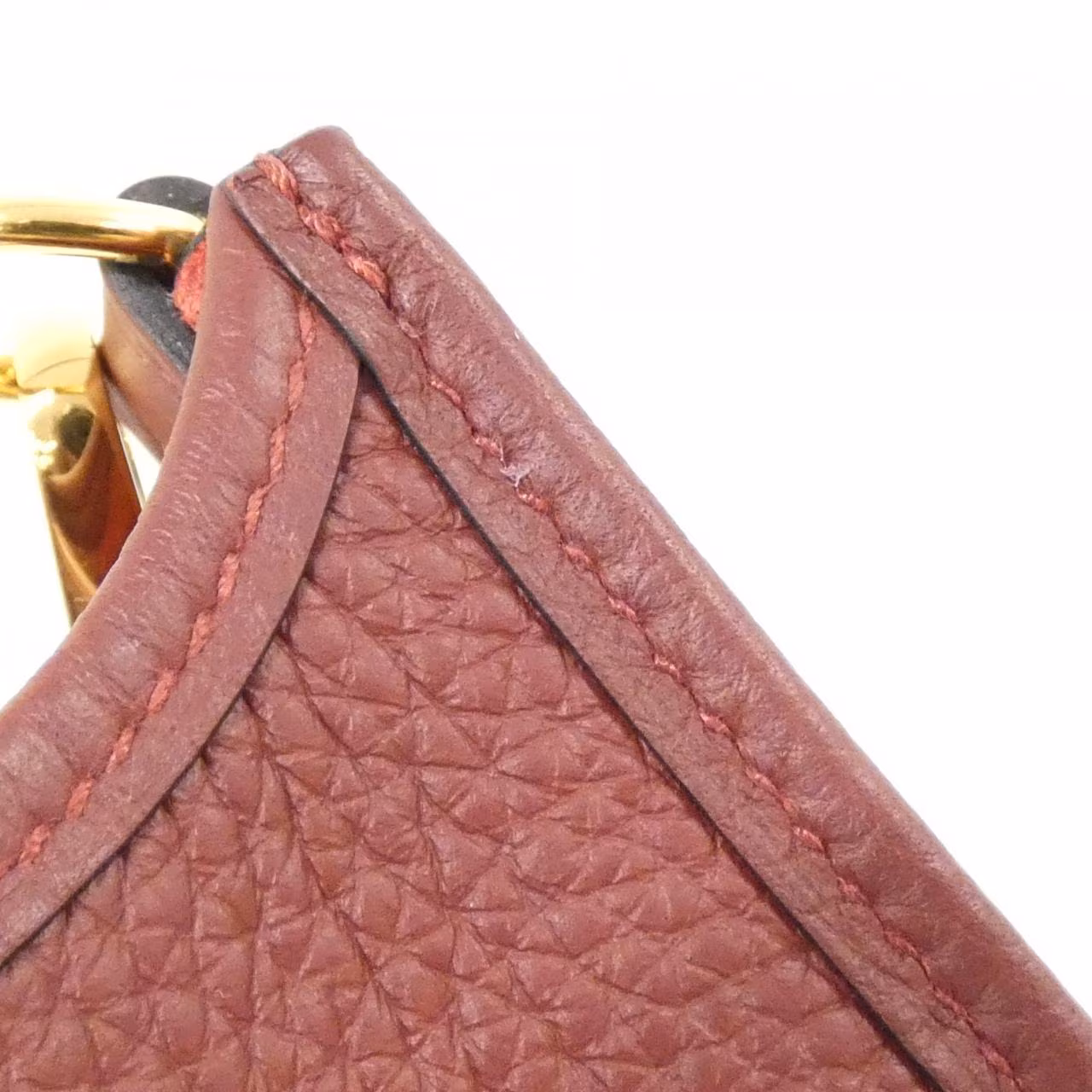 Small leather shoulder bag with perforated H on the front and woven strap.