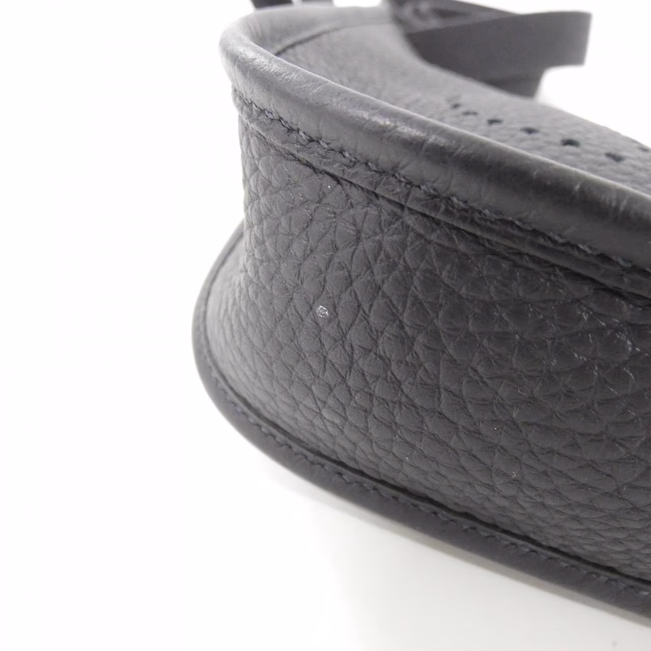 Small leather shoulder bag with perforated H motif on the front and a woven strap.