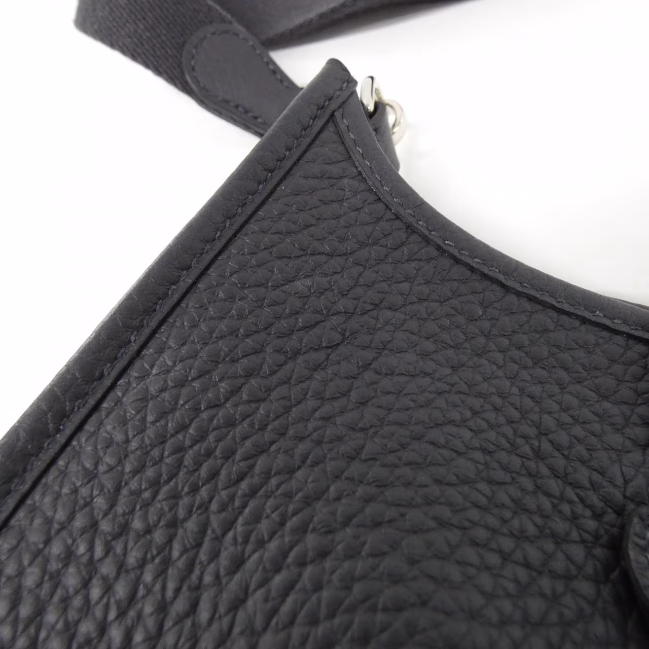 Small leather shoulder bag with perforated H motif on the front and a woven strap.