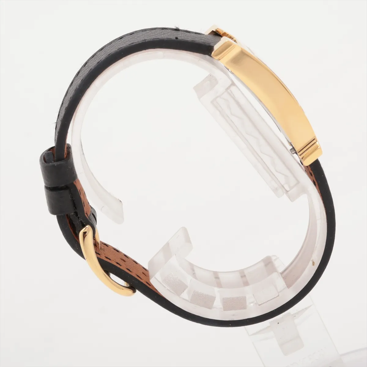 Square gold-tone watch case with white dial and slim leather strap.