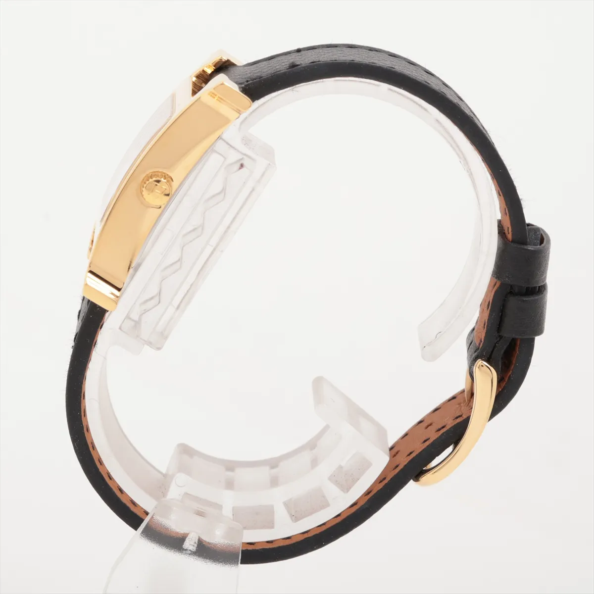 Square gold-tone watch case with white dial and slim leather strap.