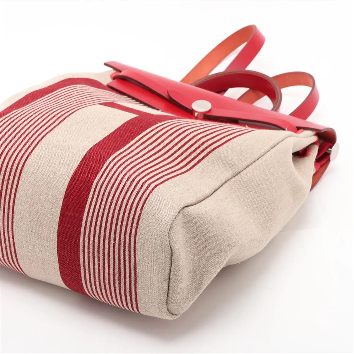 Red canvas bag with tan leather flap and base, silver clasp and a shoulder strap.