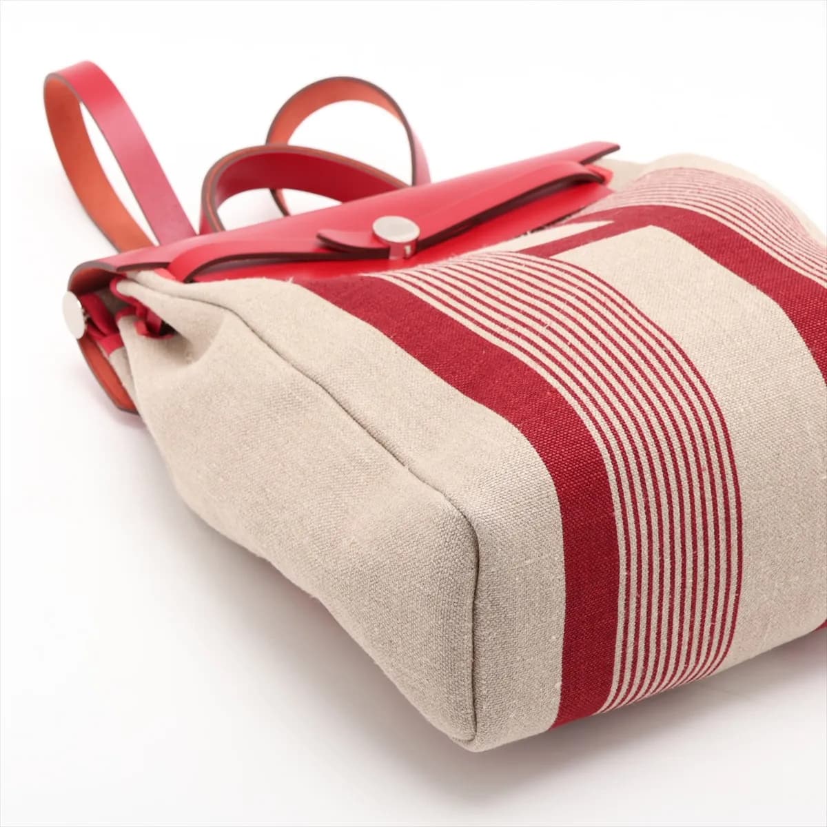 Red canvas bag with tan leather flap and base, silver clasp and a shoulder strap.
