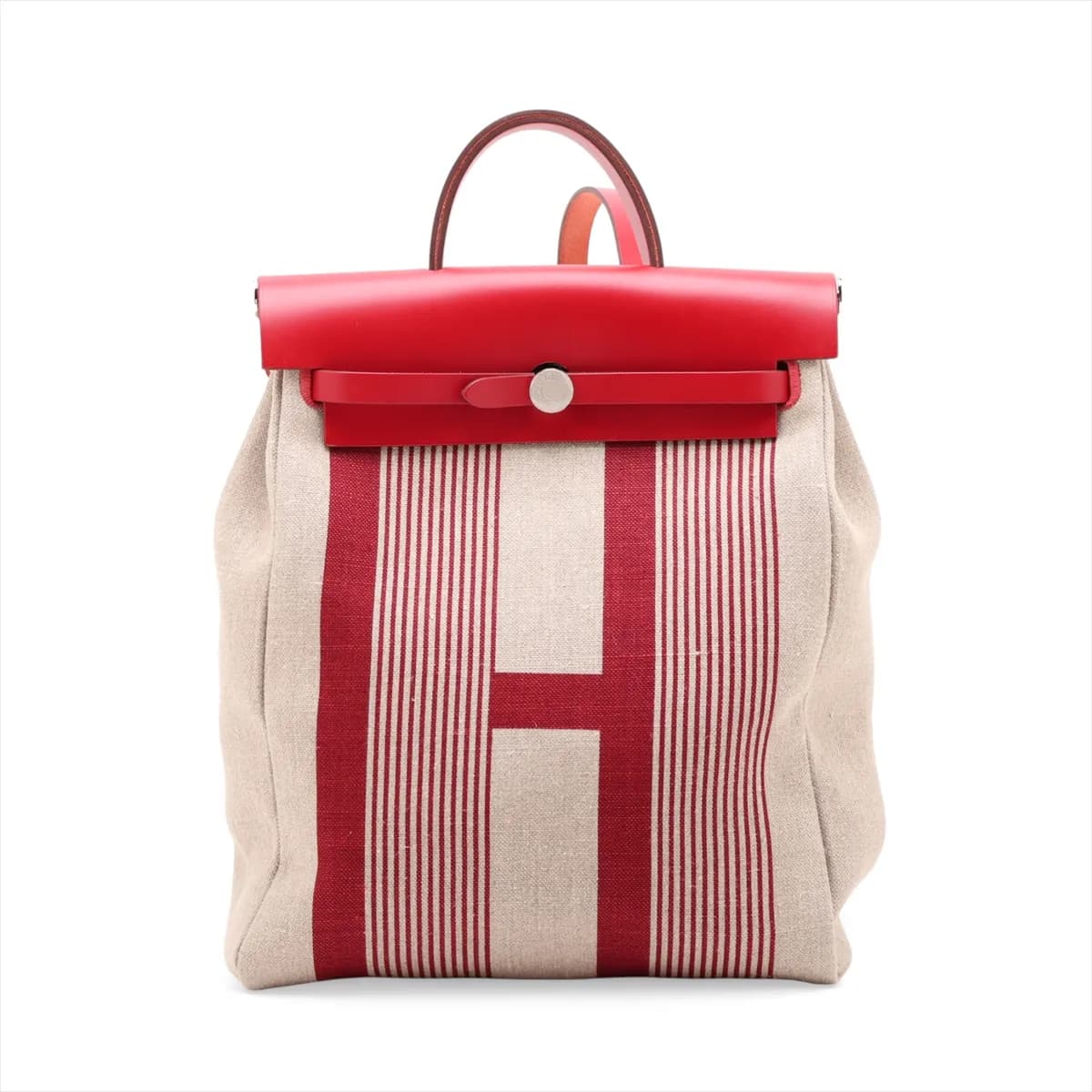 Red canvas bag with tan leather flap and base, silver clasp and a shoulder strap.