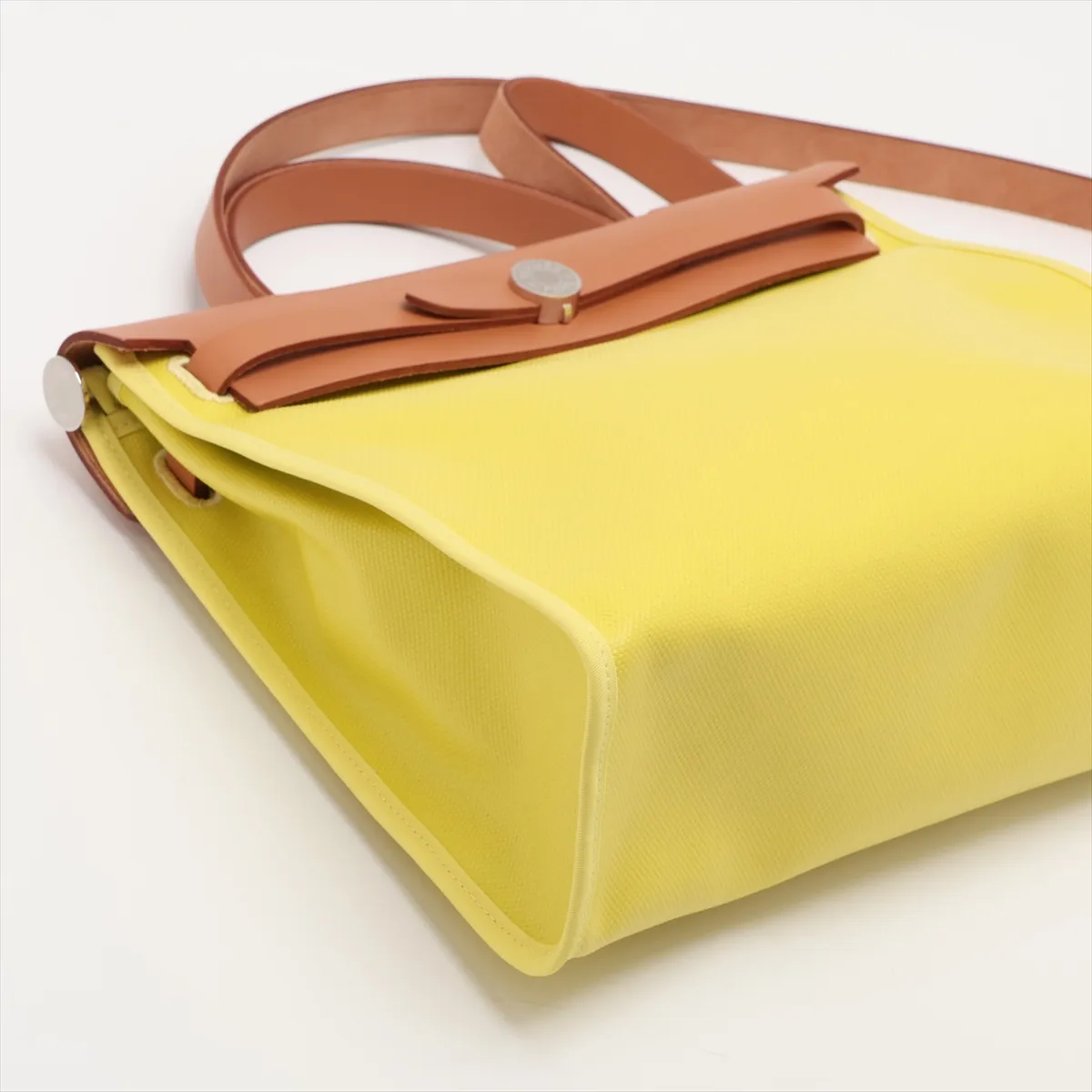 Lime green canvas bag with natural leather trim and silver-tone closure.