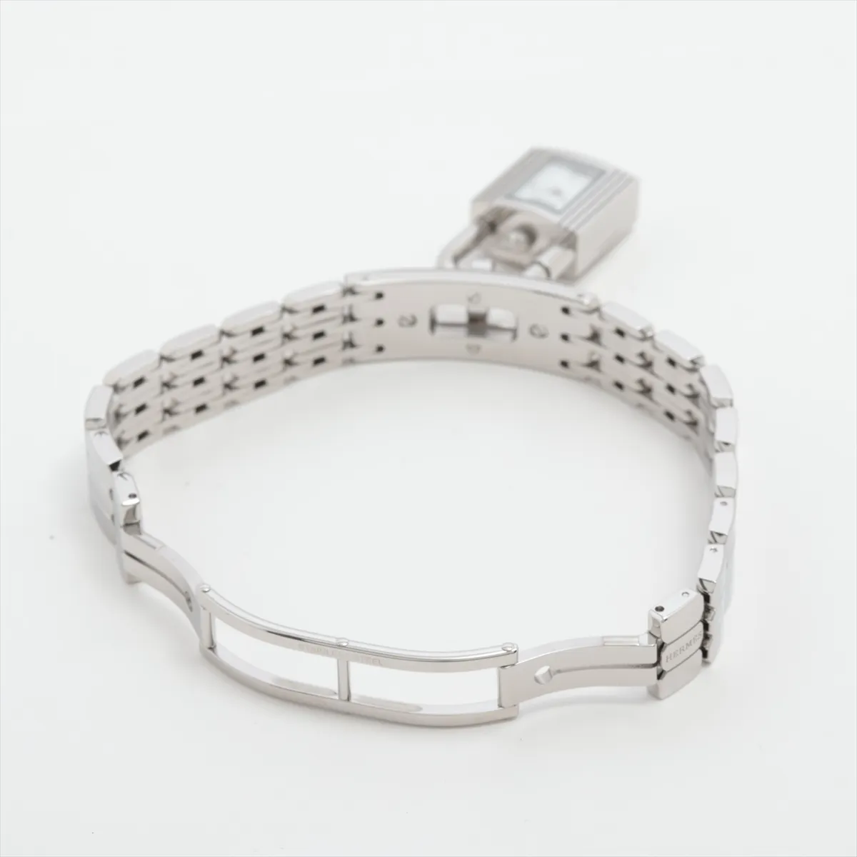Small rectangular watch with white dial on a steel strap, shown on a plain background.