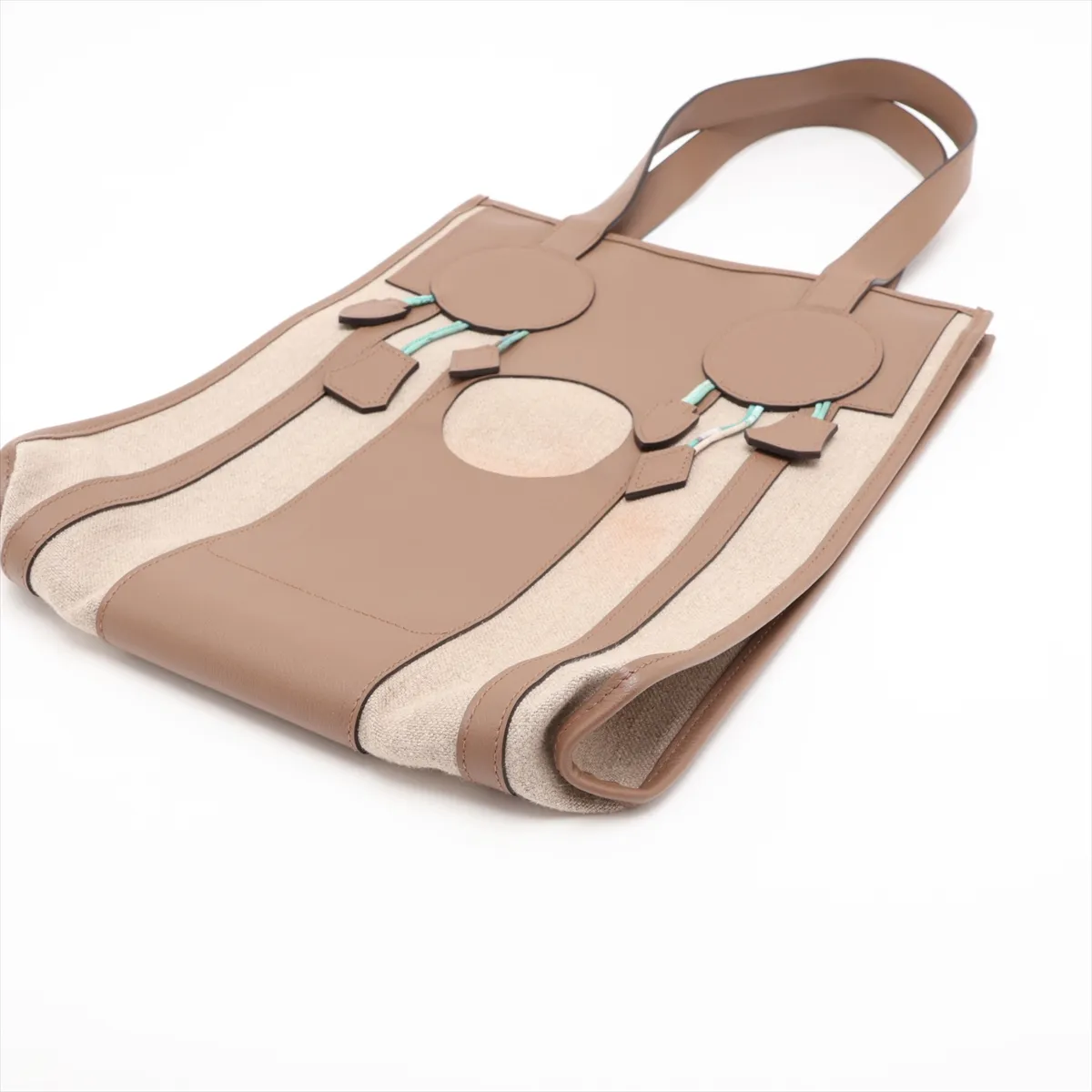 Beige canvas bag with taupe leather trim and a decorative dreamcatcher motif.