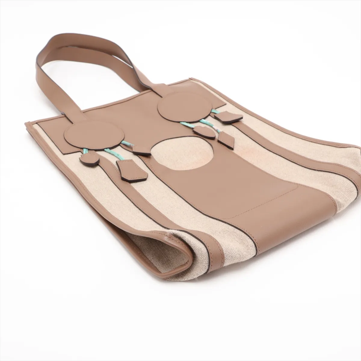 Beige canvas bag with taupe leather trim and a decorative dreamcatcher motif.