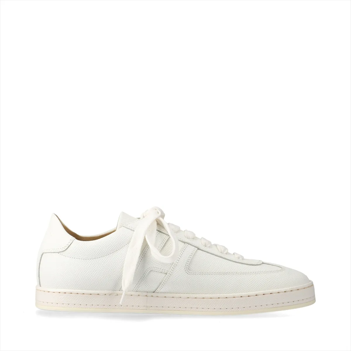 Pair of low-top white leather trainers with lace fastening, photographed on a plain background.