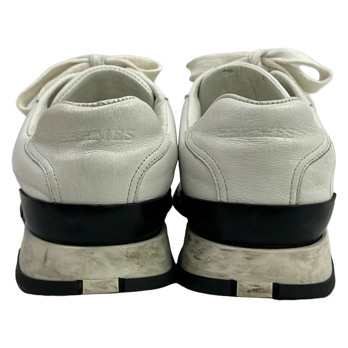 White low-top trainers with panelled uppers and chunky white soles.