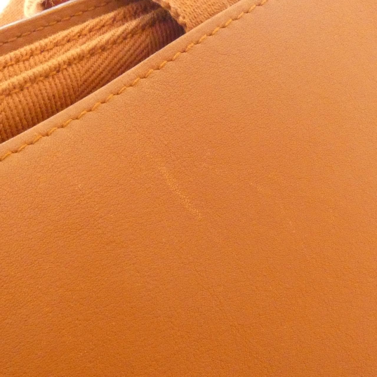 Rounded canvas and leather handbag with zip top and short handles.