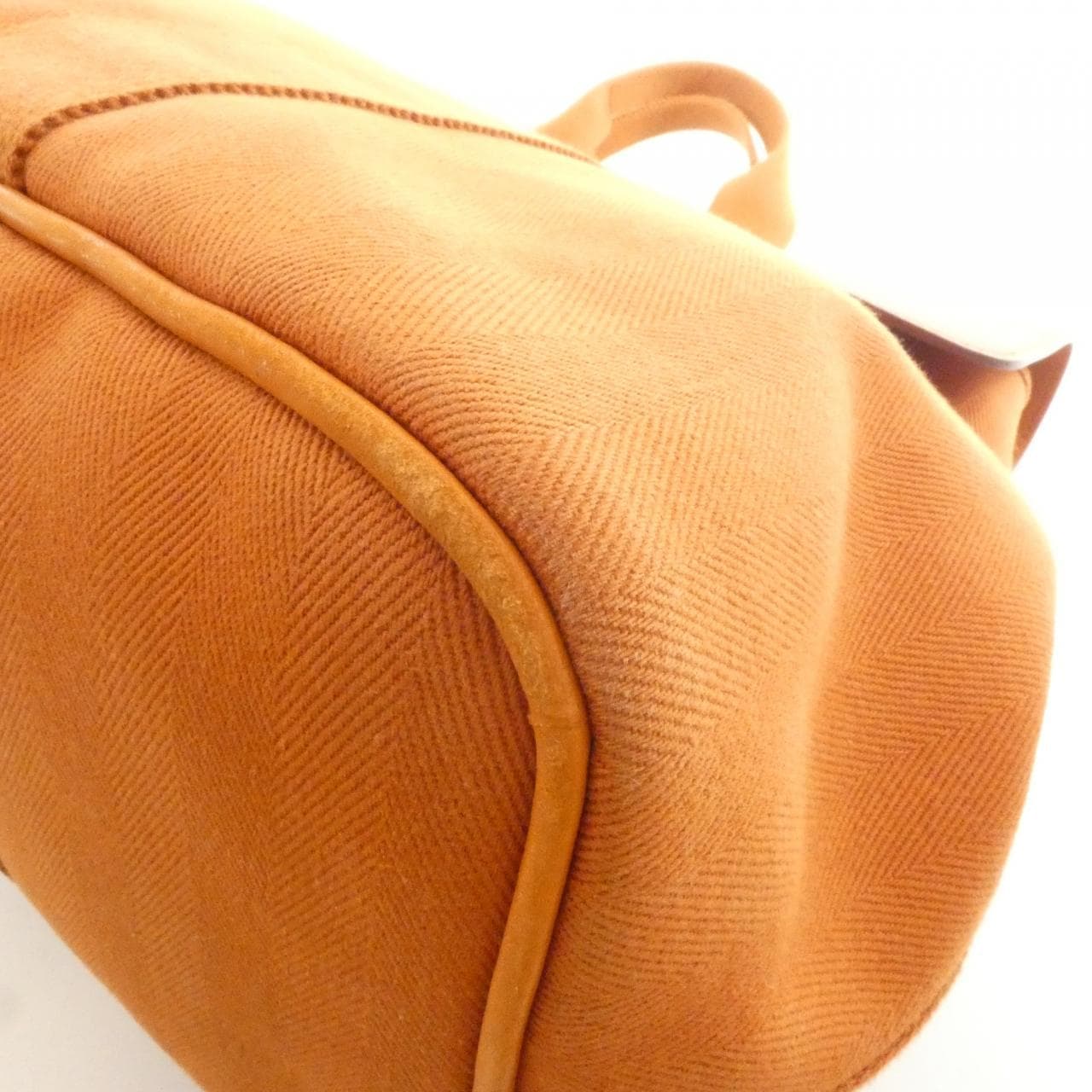 Rounded canvas and leather handbag with zip top and short handles.