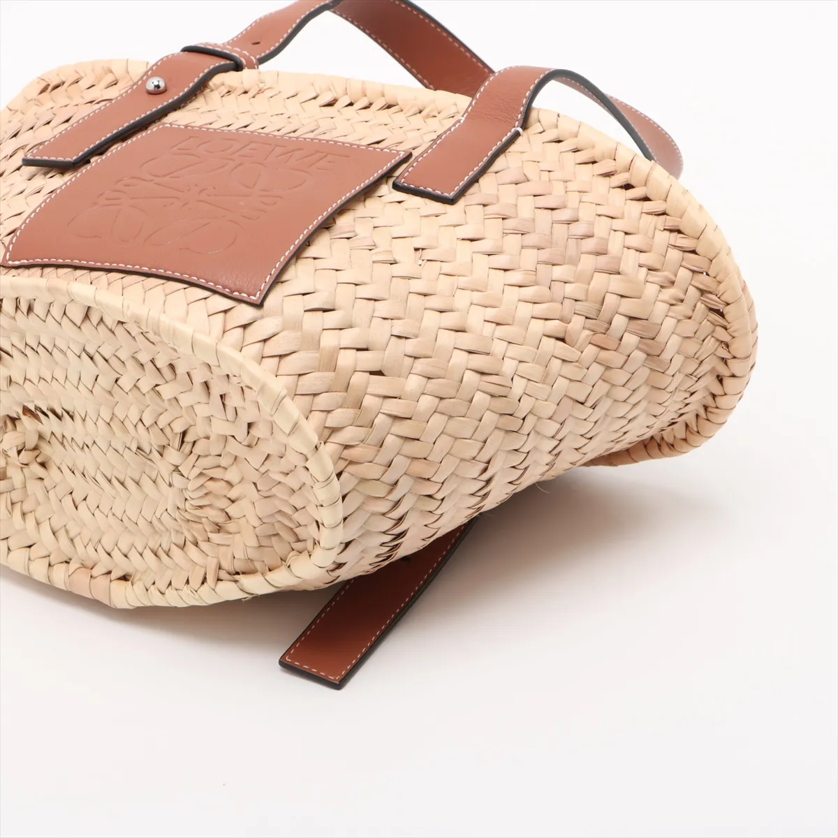 Woven natural straw basket bag with dark leather top trim and handles