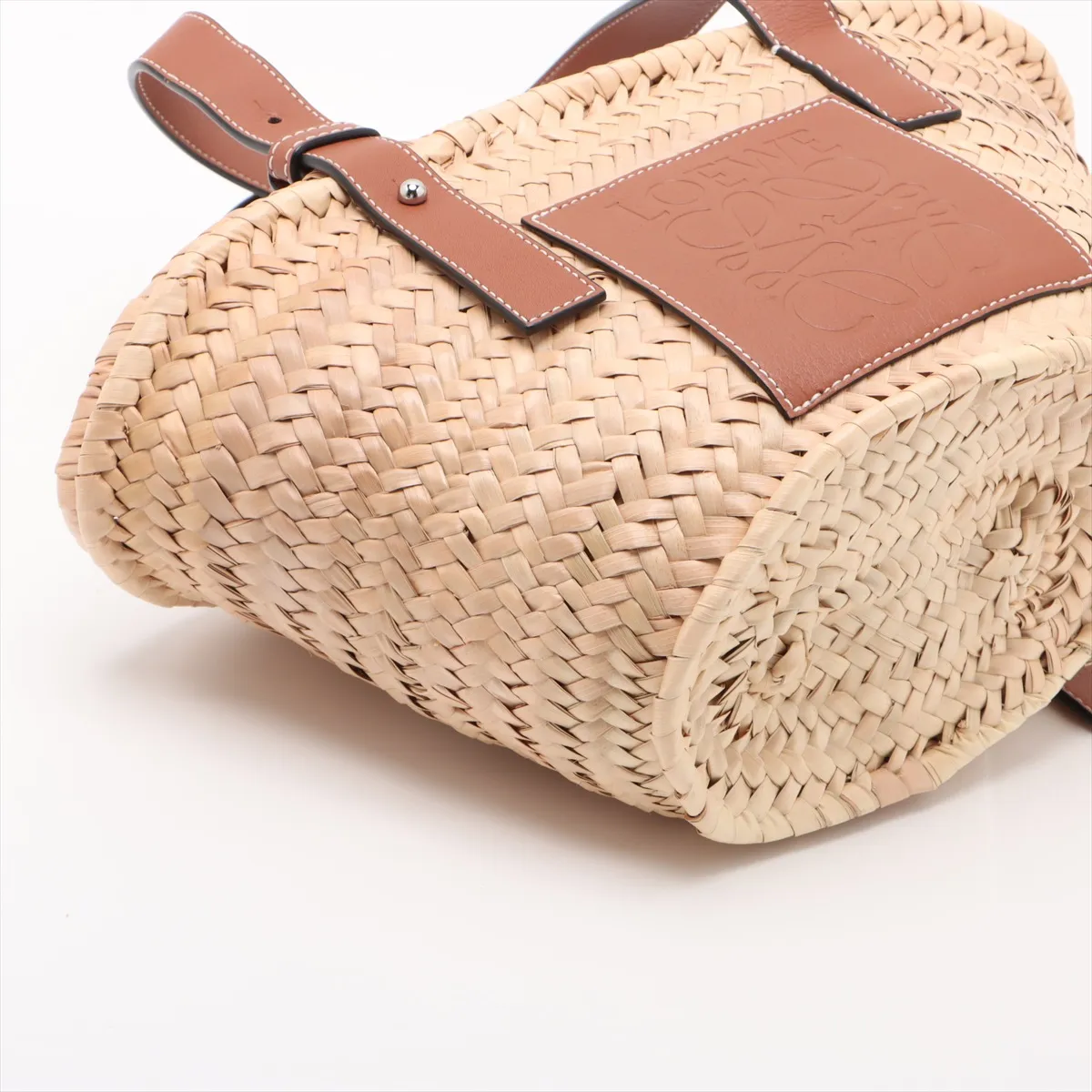 Woven natural straw basket bag with dark leather top trim and handles