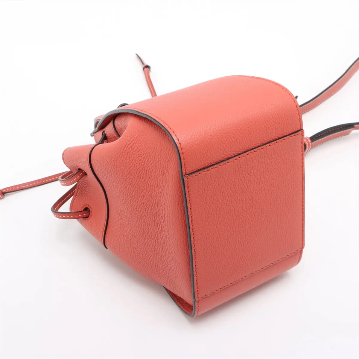 Orange leather bucket-style handbag with drawstring top and a detachable shoulder strap.