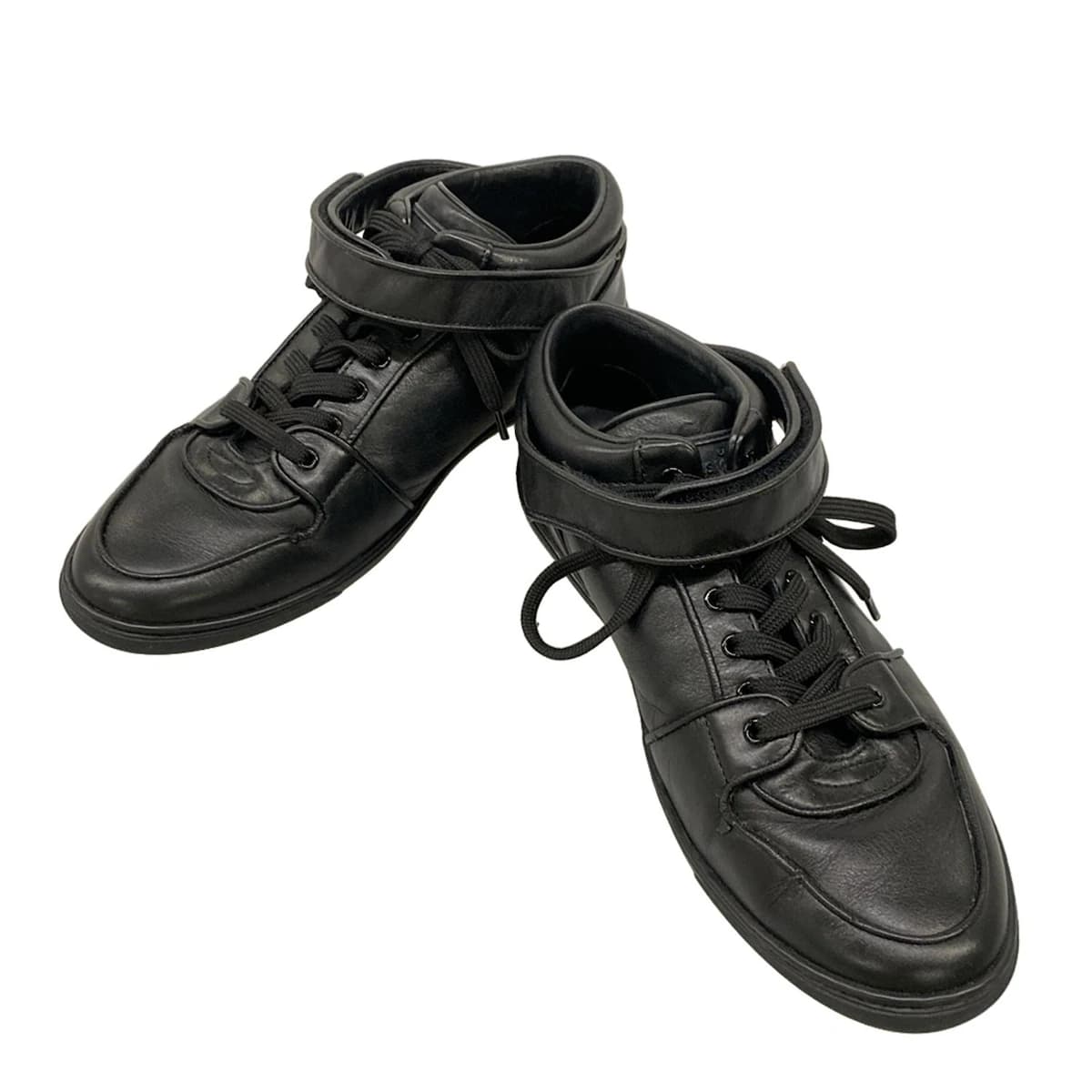 Pair of black leather low-top trainers photographed from the side.
