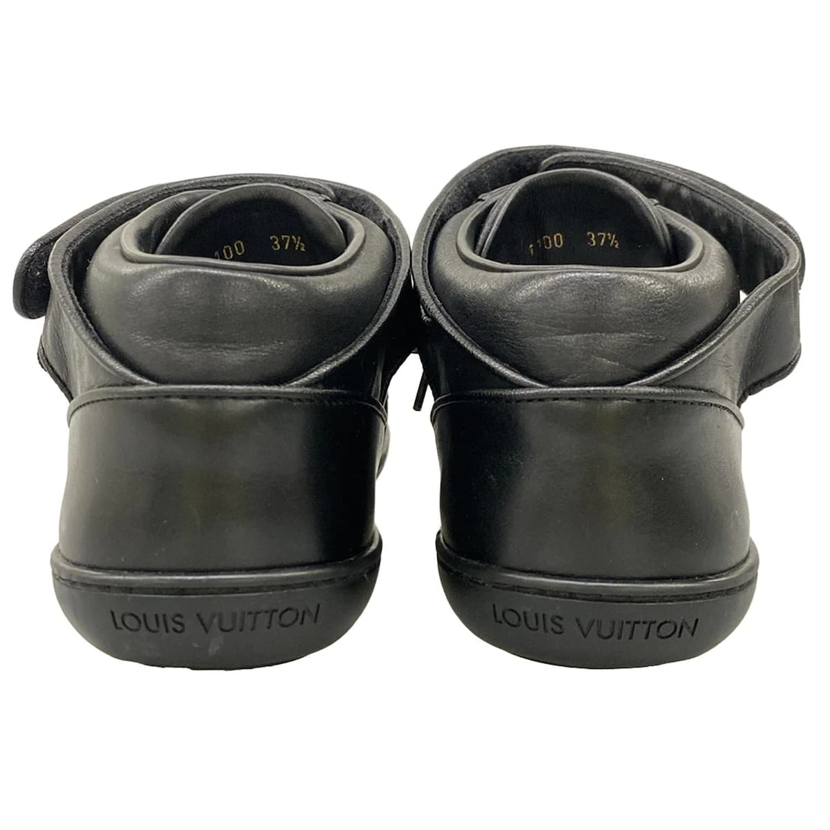 Pair of black leather low-top trainers photographed from the side.