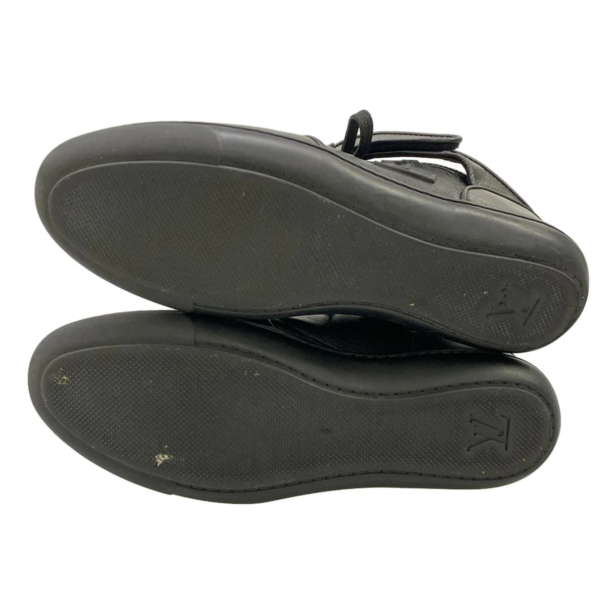 Pair of black leather low-top trainers photographed from the side.