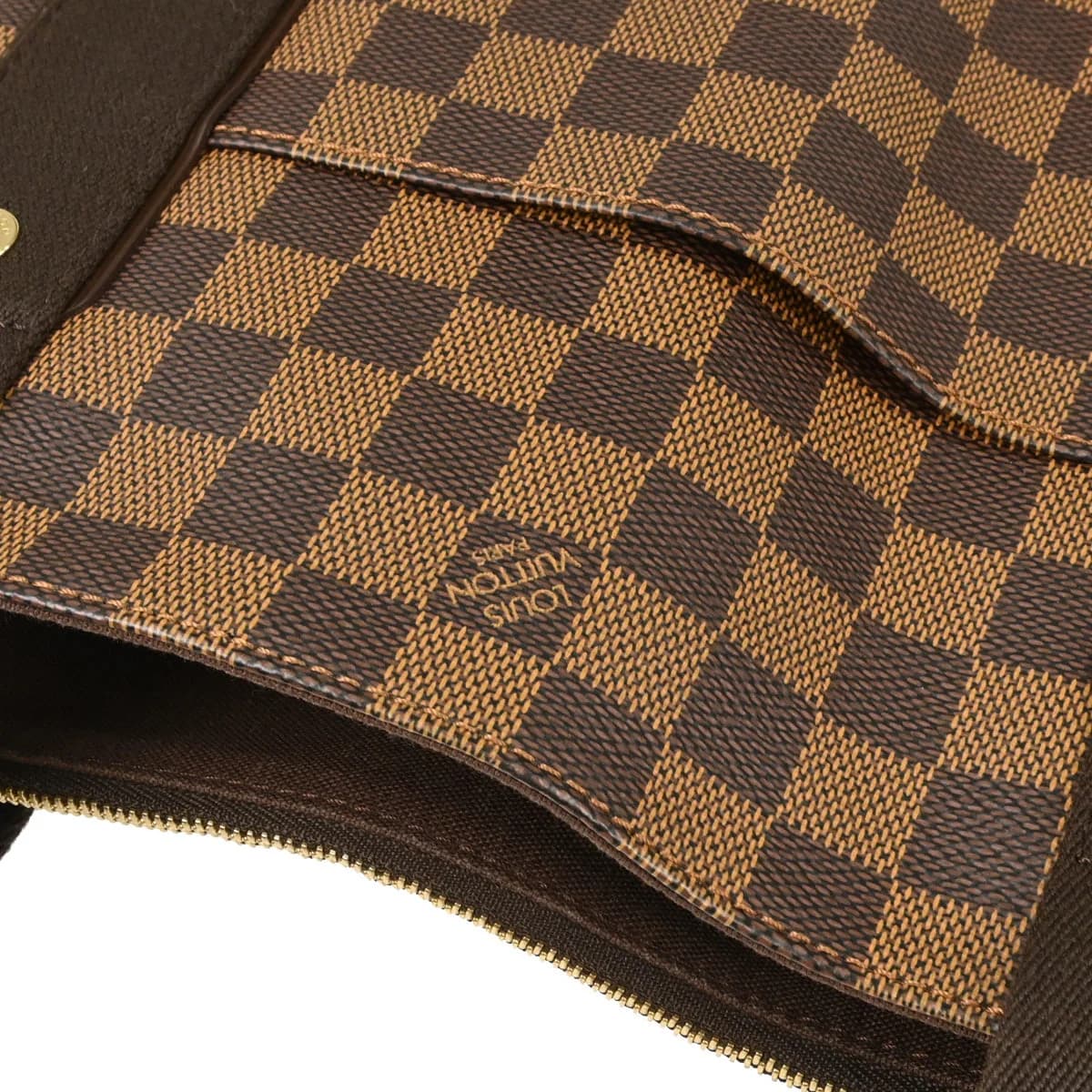 Brown checked canvas tote bag with tan leather handles and trim, standing upright.