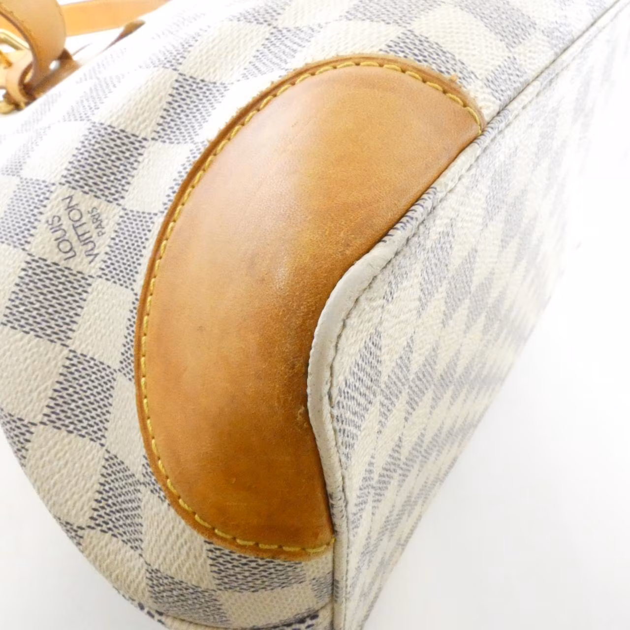 Light blue and white checked canvas shoulder bag with tan leather handles.