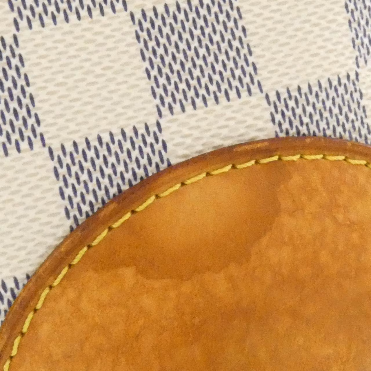 Light blue and white checked canvas shoulder bag with tan leather handles.