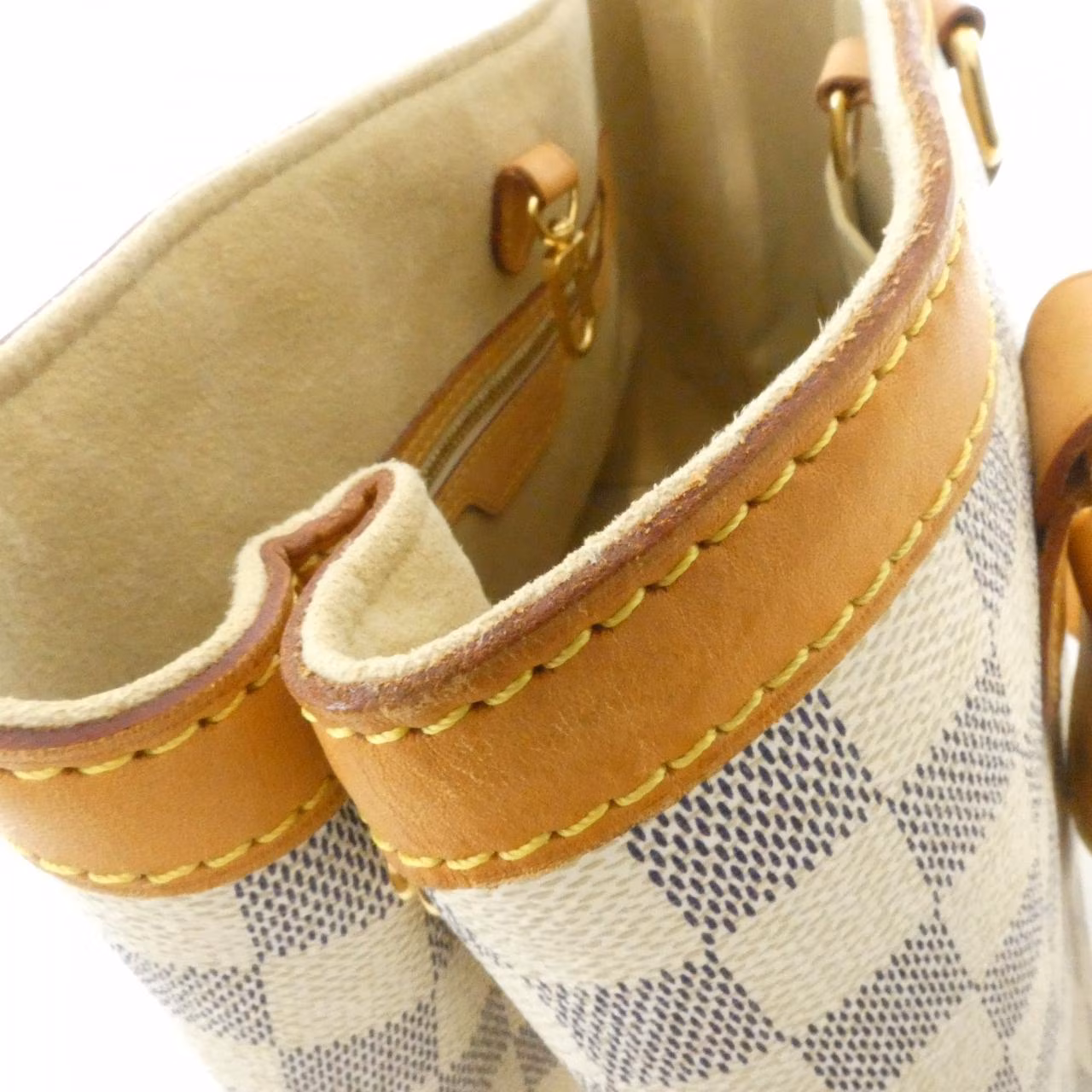 Compact checked canvas shoulder bag in pale blue and white with tan leather straps.