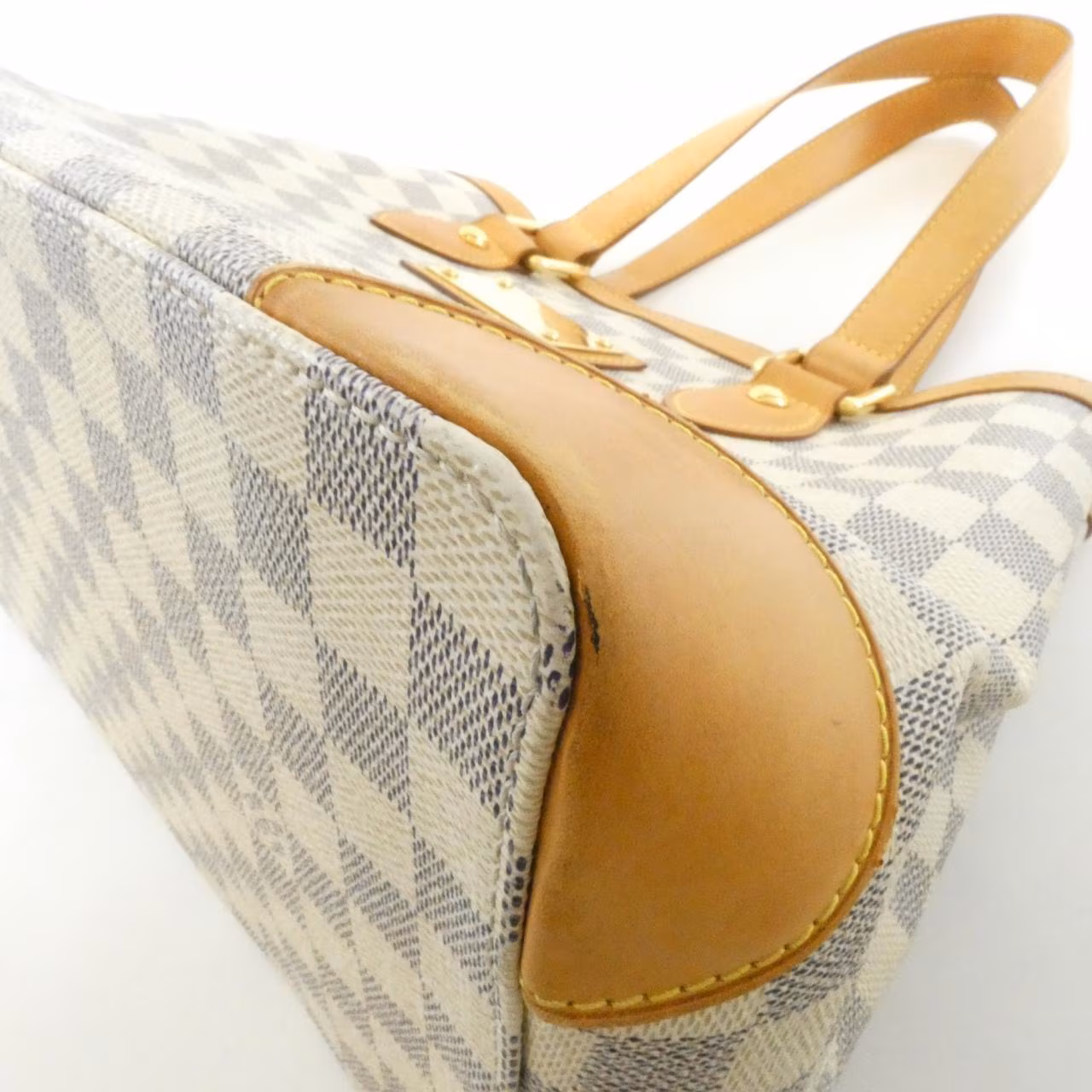 Compact checked canvas shoulder bag in pale blue and white with tan leather straps.