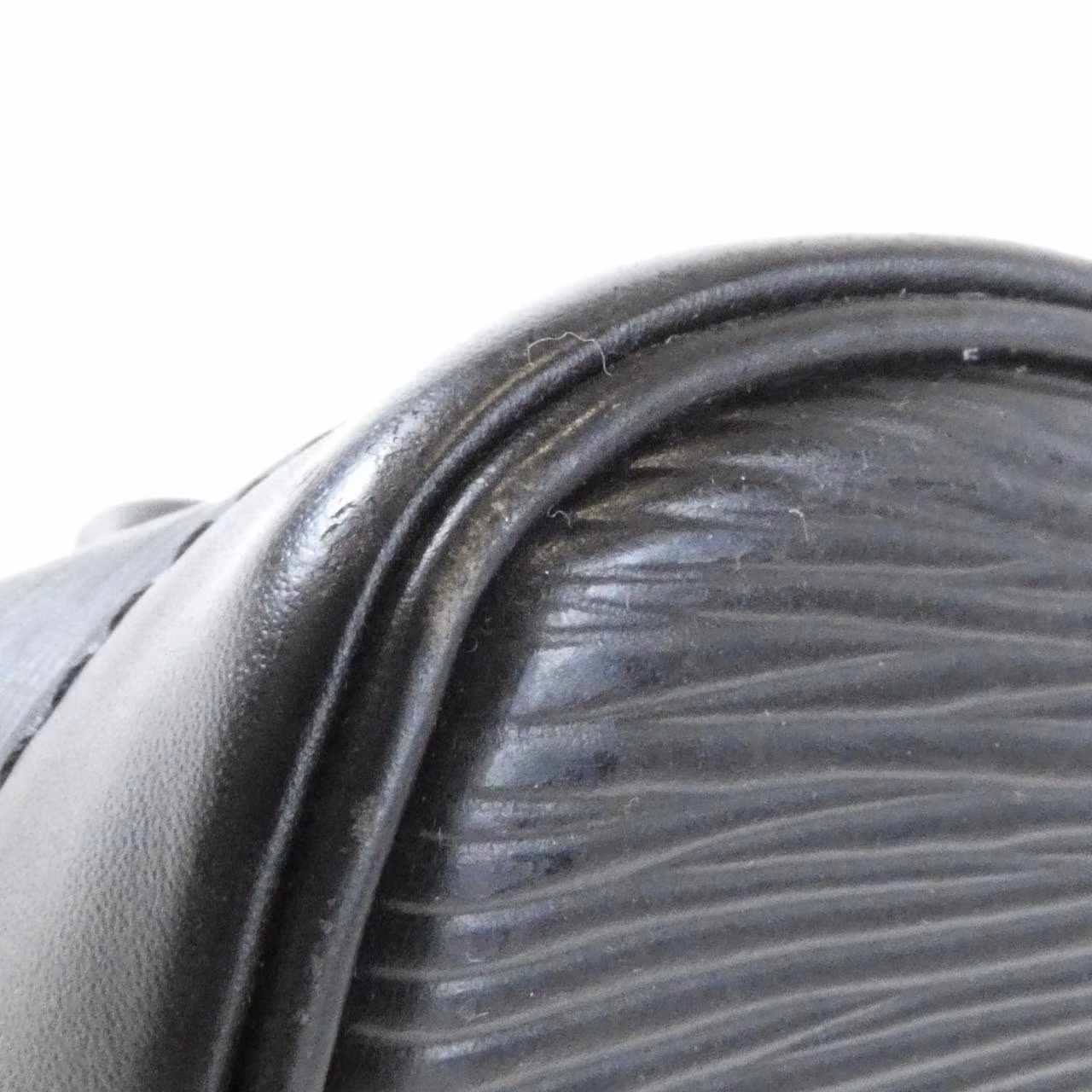 Domed textured leather handbag with rolled top handles and a curved zip opening.