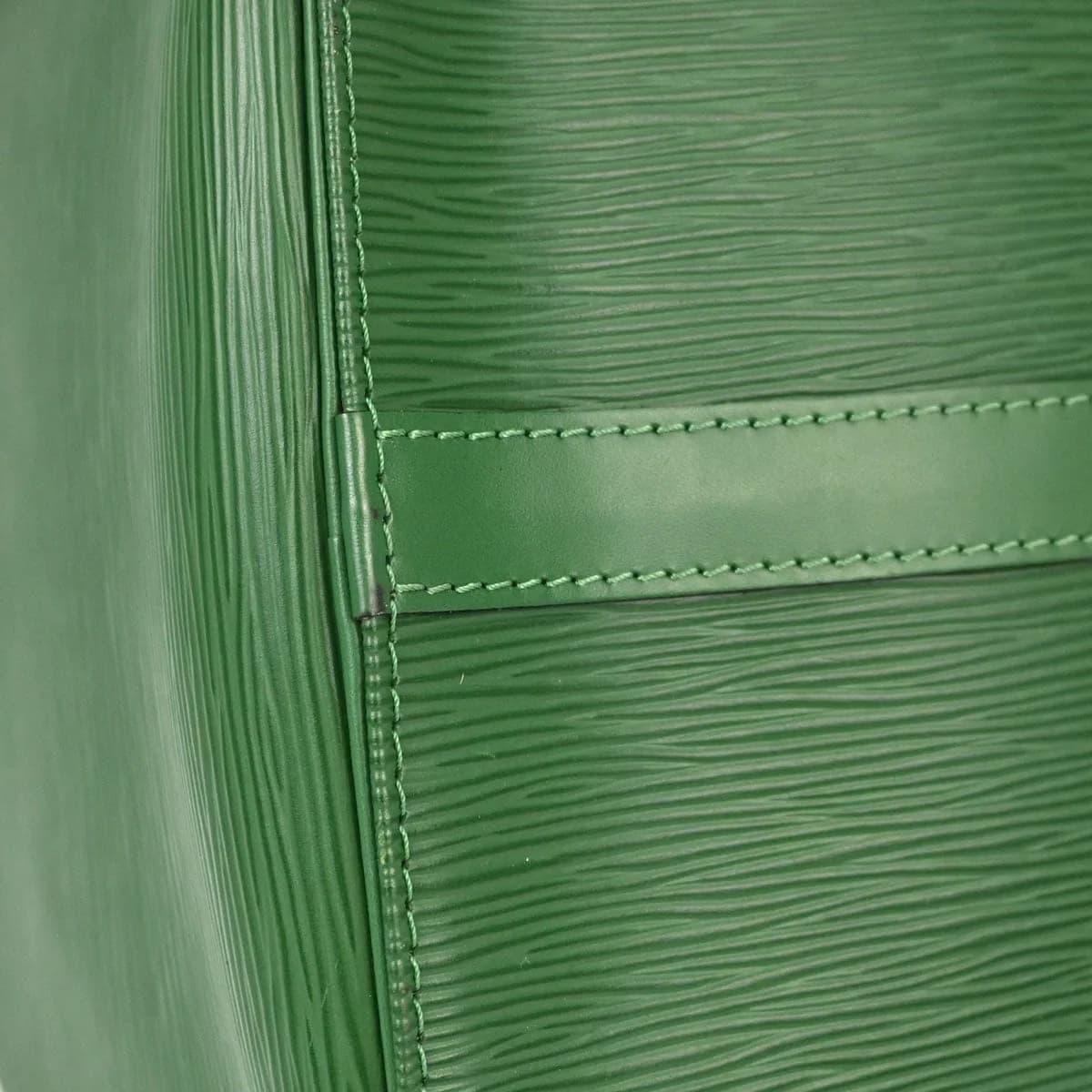 Green leather duffle bag with rolled handles, a zip top and a hanging leather tag.