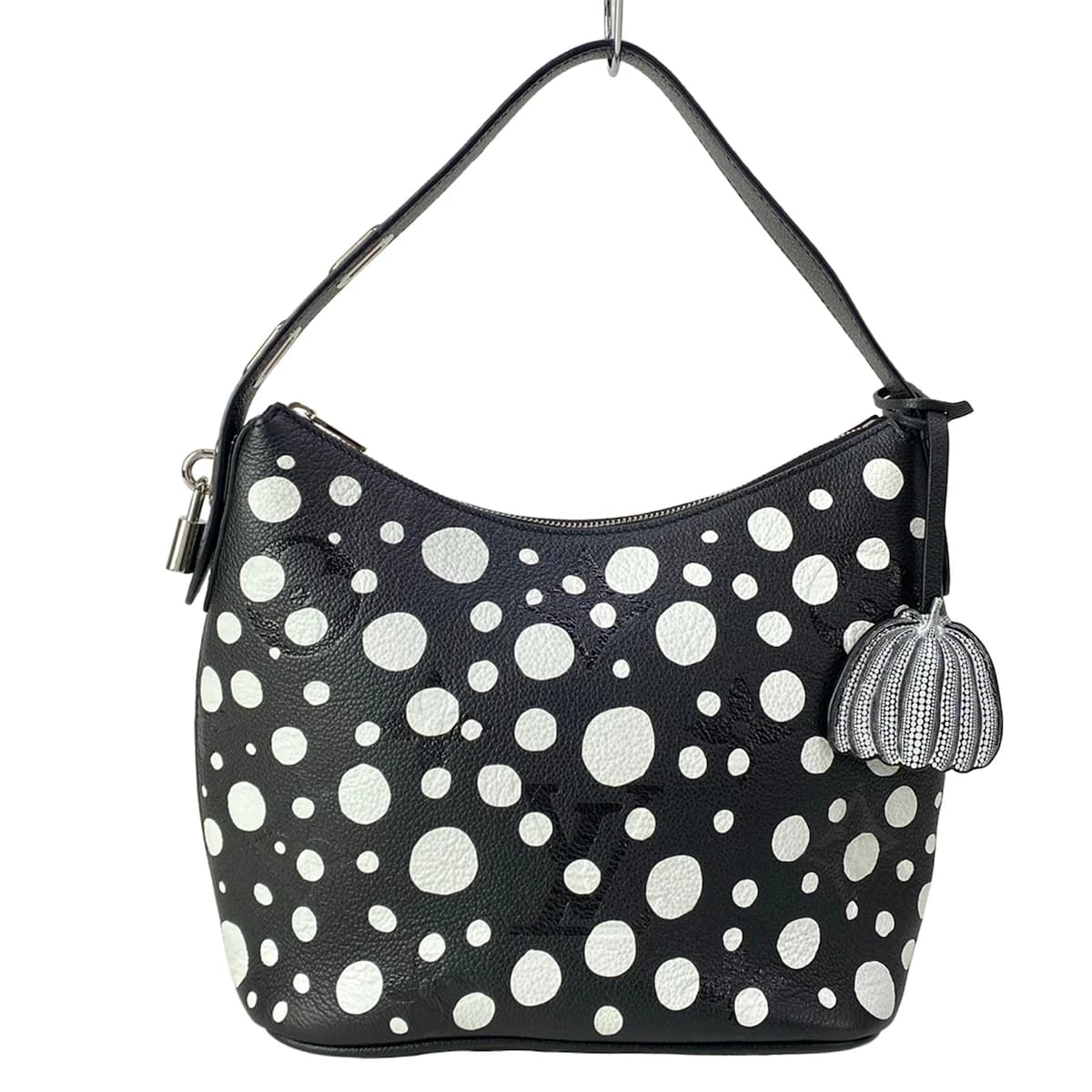 Patterned handbag covered in repeating dot motifs with leather trim and a top handle.