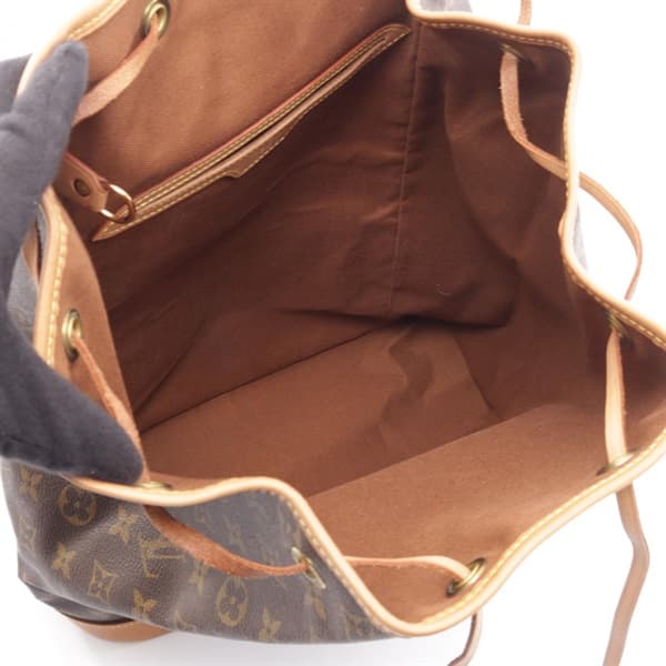 Brown monogram-patterned canvas backpack with leather straps and buckled flap pockets.