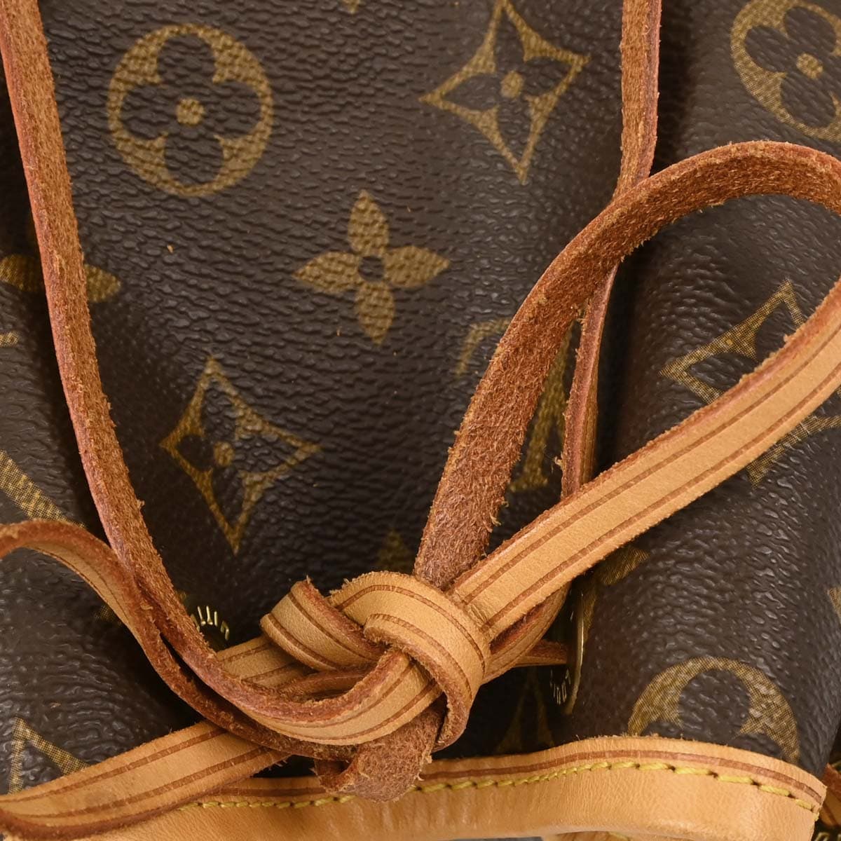 Brown monogram canvas bucket bag with drawstring top and single shoulder strap.