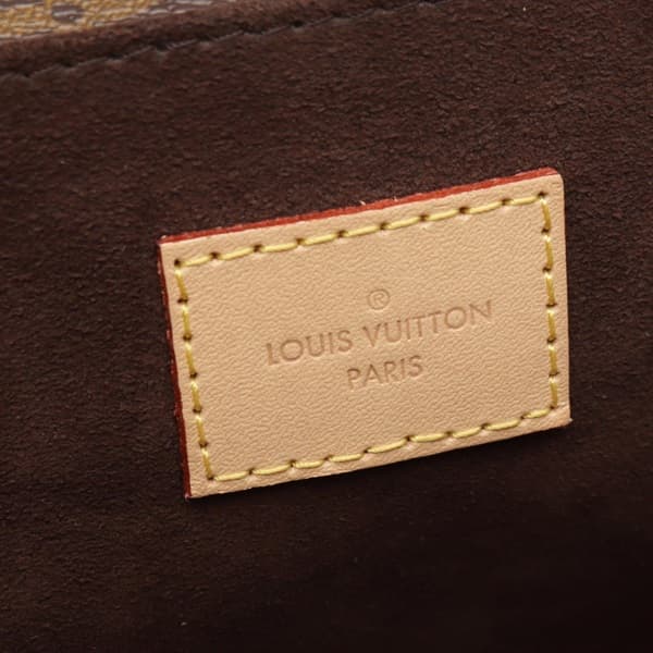 Product photograph of a structured monogram-canvas flap bag with a top handle.