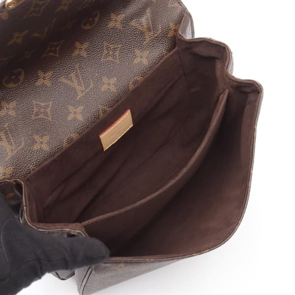 Product photograph of a structured monogram-canvas flap bag with a top handle.