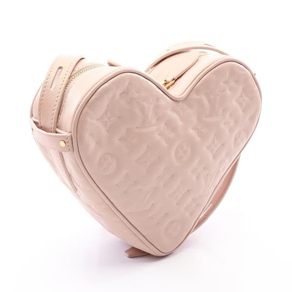 Product photograph of a pink heart-shaped bag with a chain and leather shoulder strap.